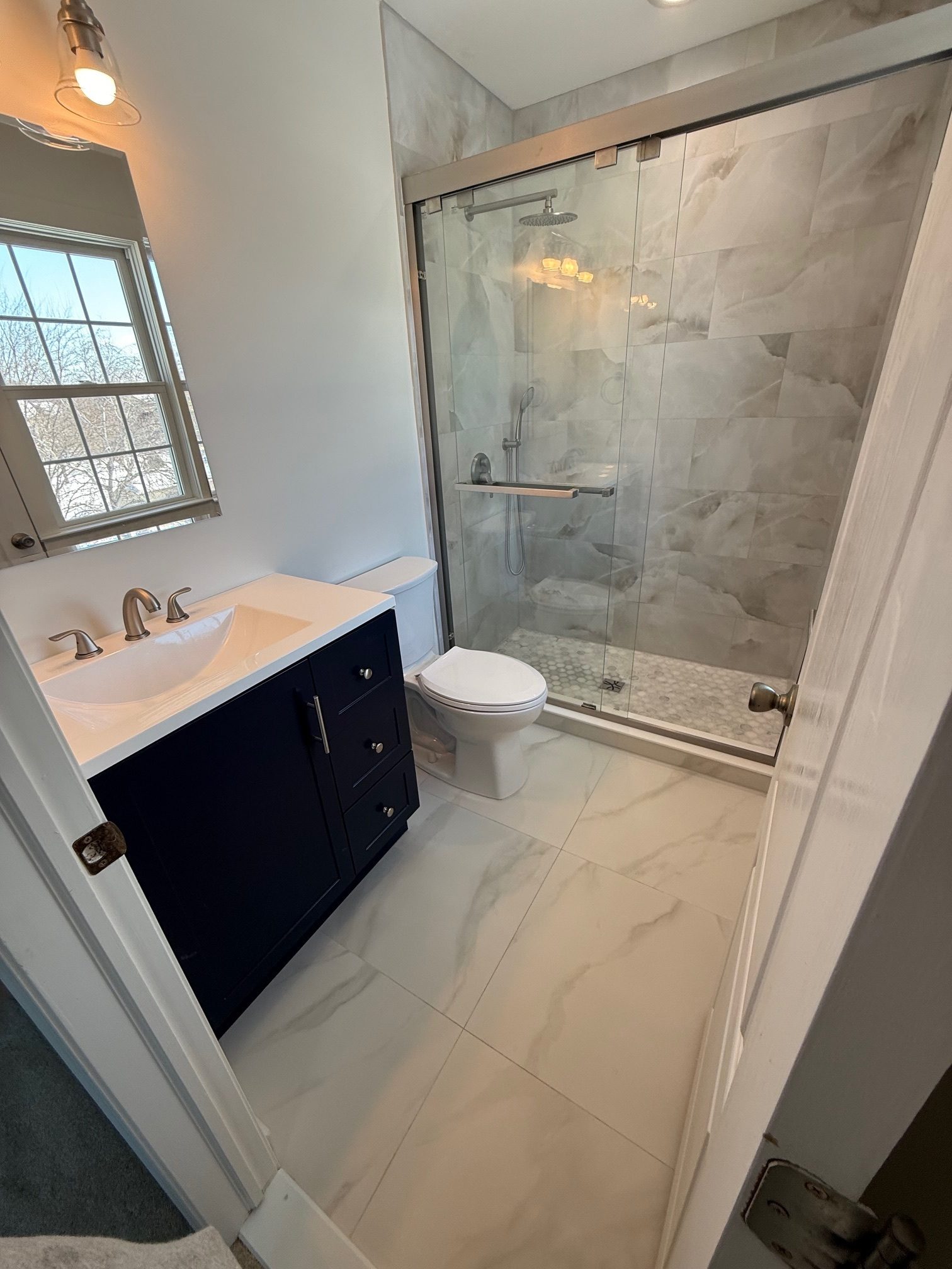 Semi-frameless sliding shower door on a tiled shower remodeled by TGF Remodeling
