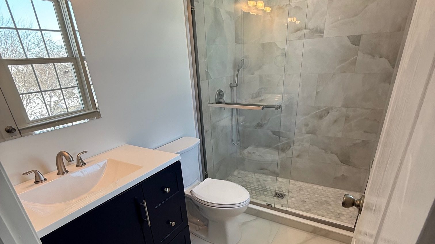 Semi-frameless sliding shower door on a tiled shower remodeled by TGF Remodeling